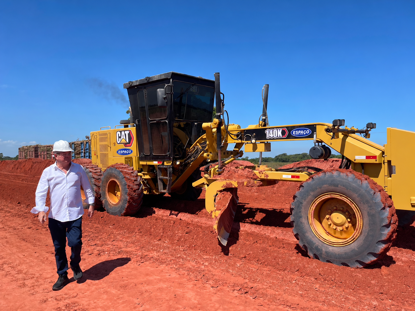 Motoniveladora CAT em obra com identidade visual da Espaço Construções